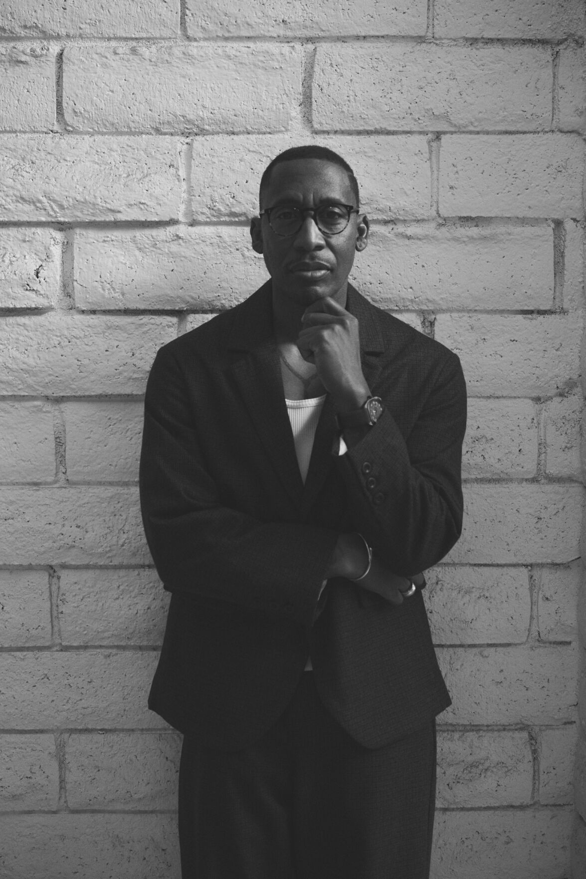 Raphael Saadiq press photo black and white 2025 artist stands against a light-colored brick wall